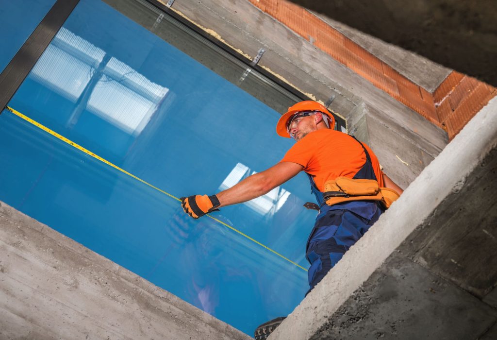 Worker measuring large window installation